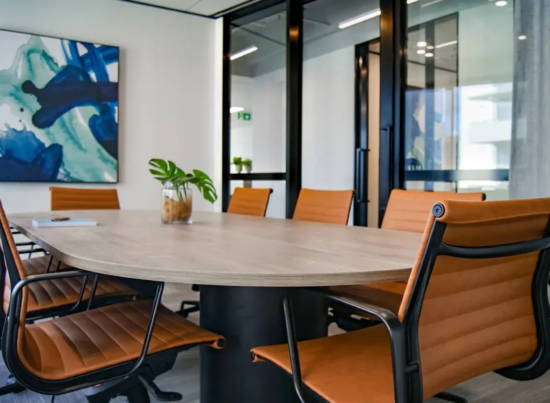 Sala de reuniones con una mesa de madera y sillas naranjas